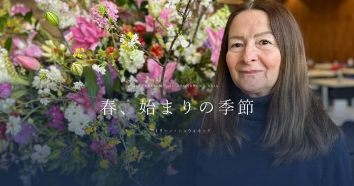 Smiling woman with long brown hair beside a large, colorful flower bouquet; headline in Japanese reads '春、始まりの季節'.